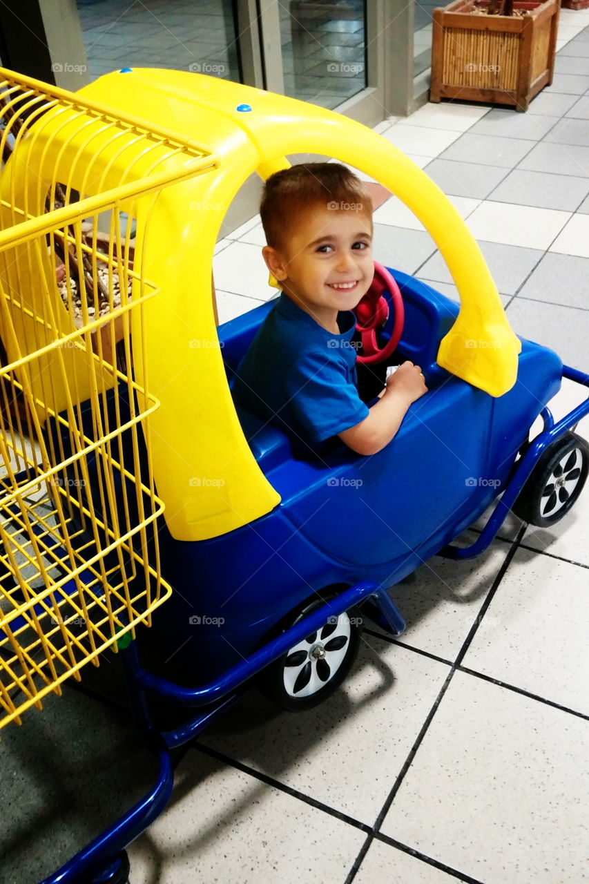 Happy kid.  enjoy travel the yellow car cart 