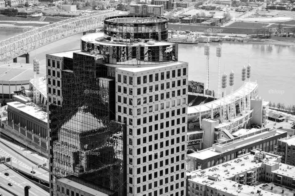 Black and white image of a cityscape with the focus on a glass sided building with a reflection of another building on it