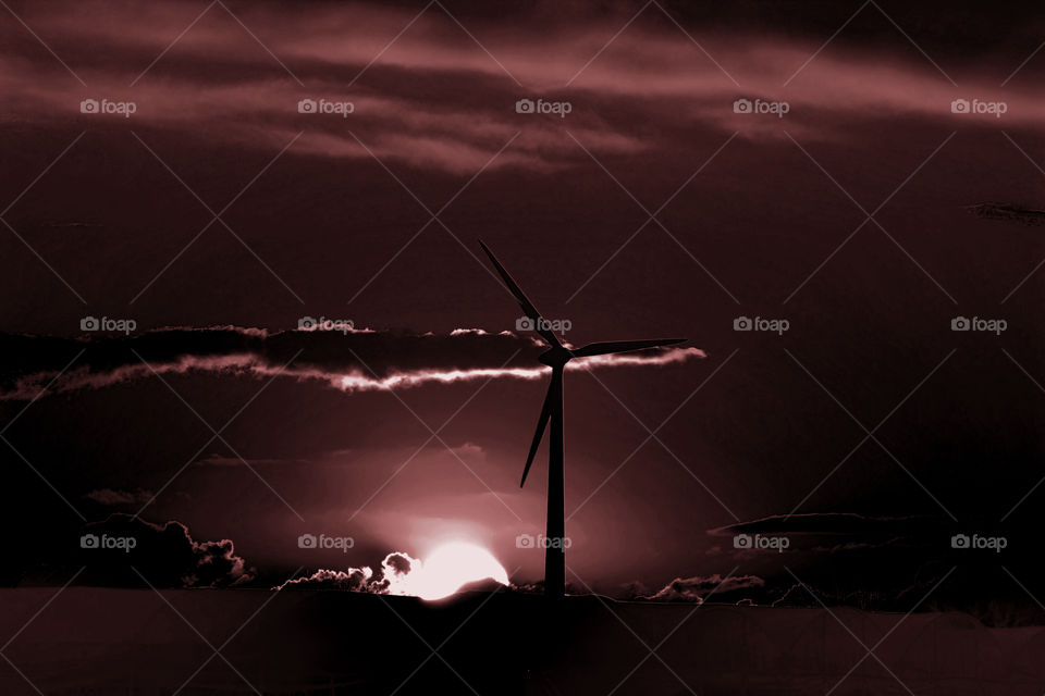 Back-lit wind turbine at sunset. Eerie atmosphere