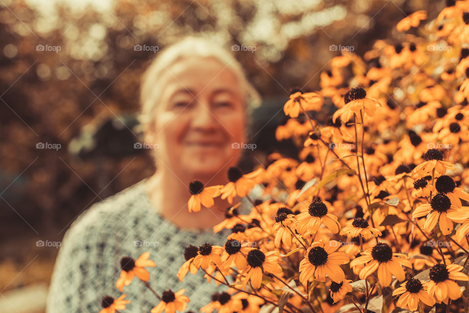 Selective focus to autumn flowers with blurred person in background.