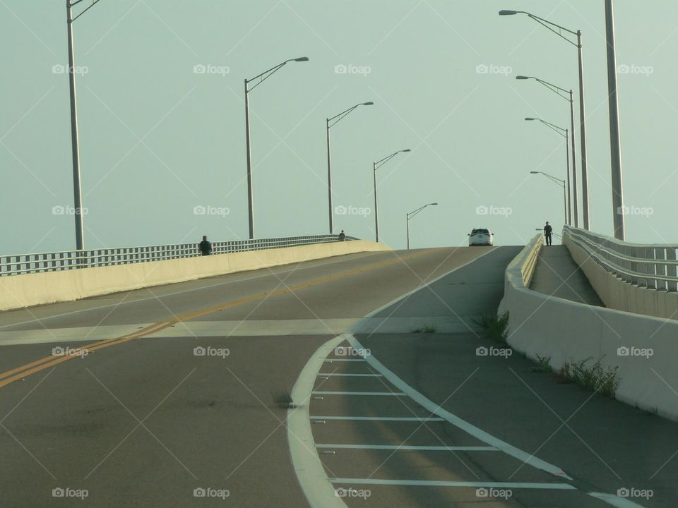 Road trip going towards the beach in central eastern Florida by the Atlantic Ocean meeting some cars on the opposite side of the road on a curved and nice high bridge with street lights.