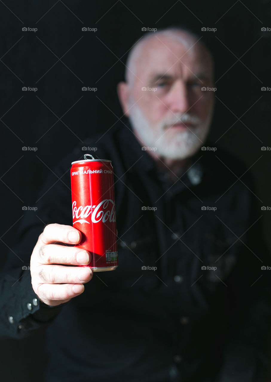 Portrait of handsome man. Man drink Coca-Cola, black background 