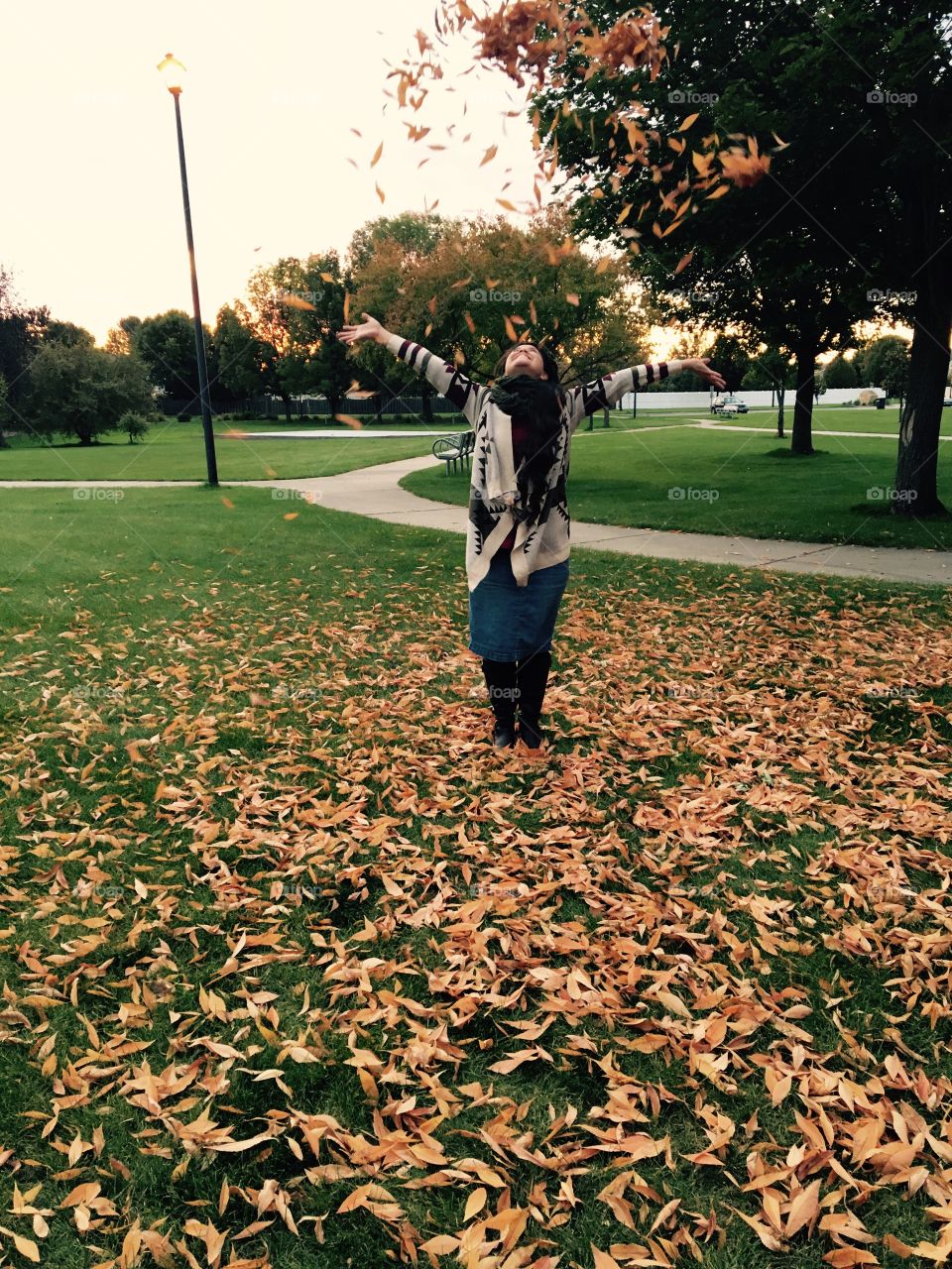 Girl throwing autumn leaves at park