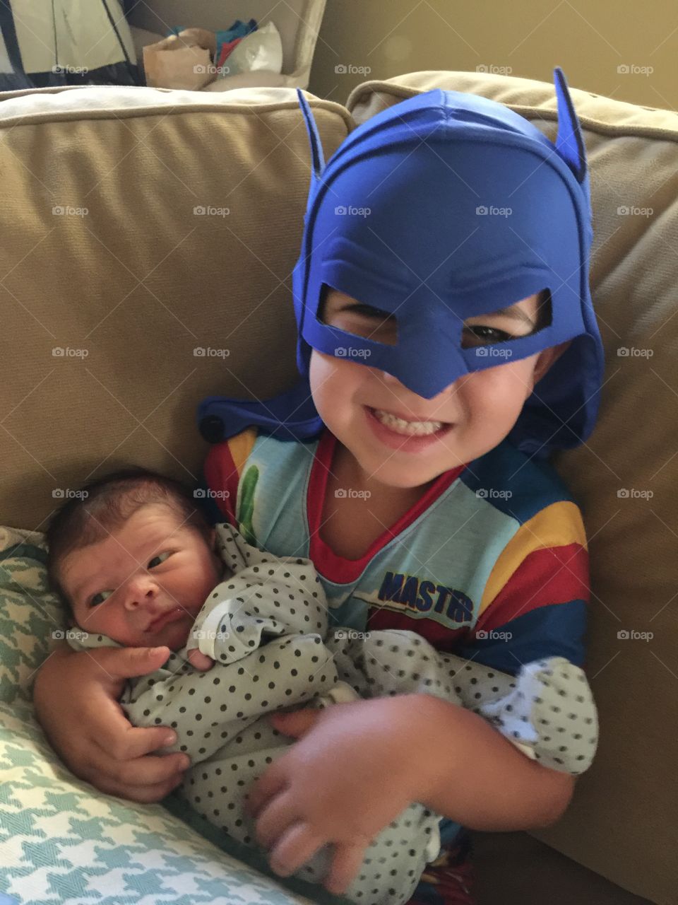 Brothers. Older brother with Batman mask on holding newborn brother. 