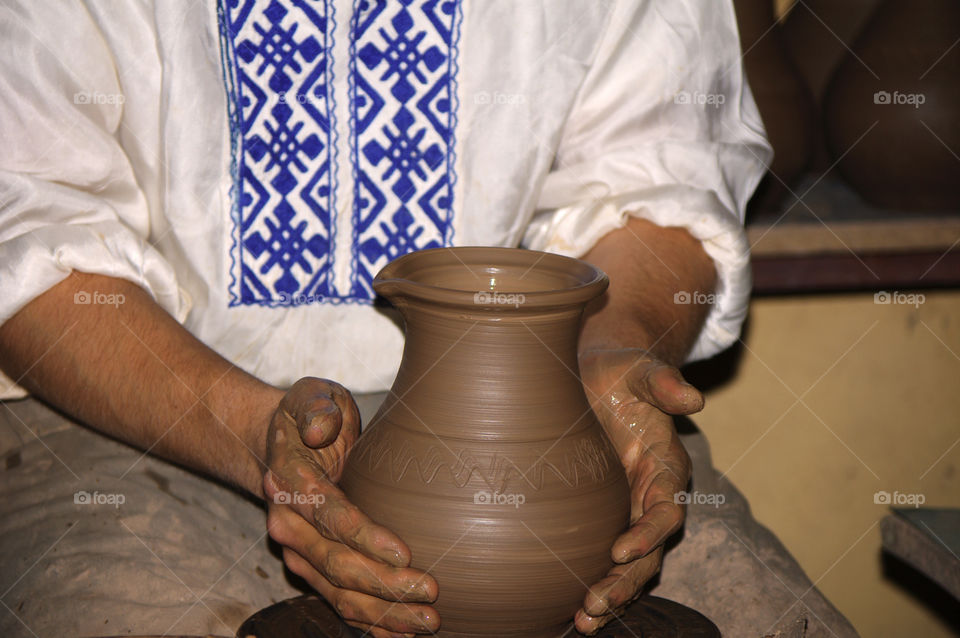 man makes a jug out of clay.