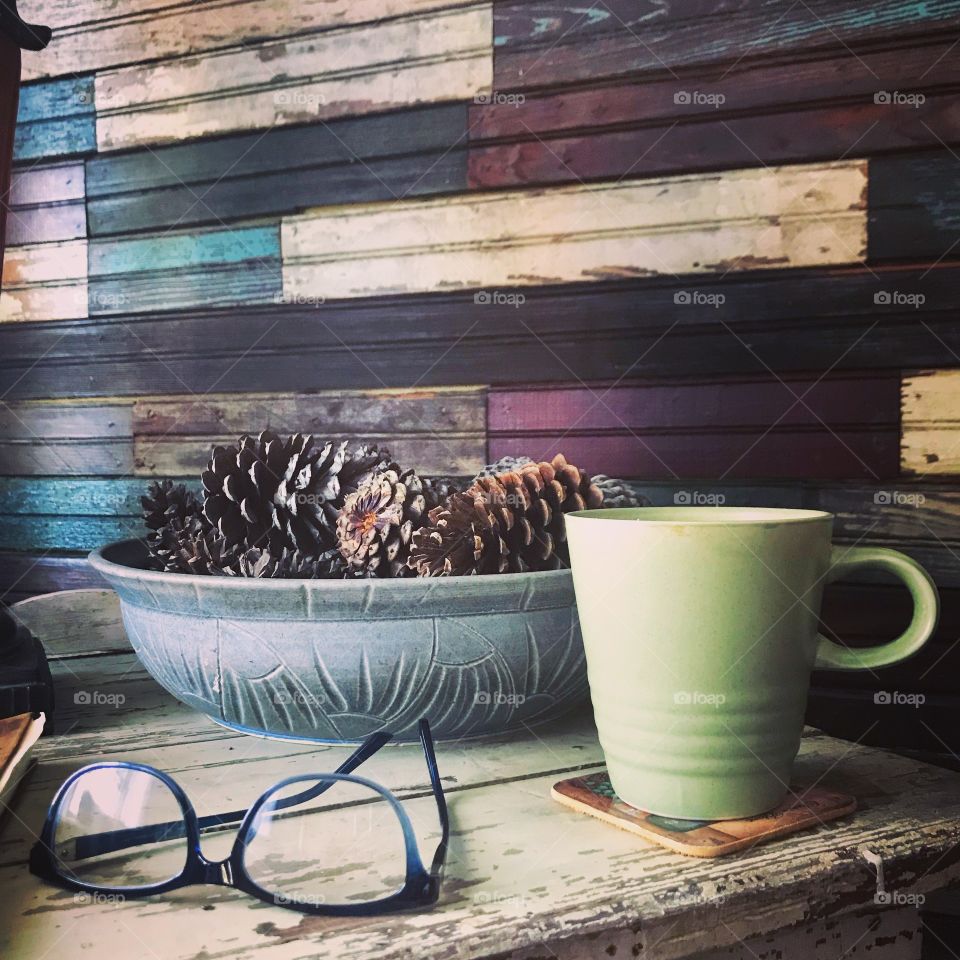 Glasses, coffee, and pine cones in front of a shiplap wall 