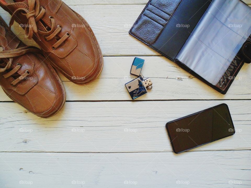 Brown leather men's shoes, notebook, cigarette lighter and smartphone