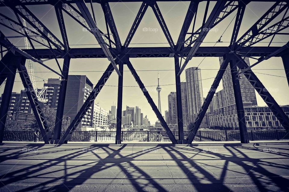 Shadows of a bridge on the street with the magnificent cn tower in the distance