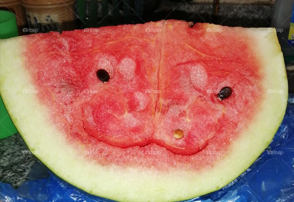 Smiley watermelon with two black seeds that say, "Smile and tomorrow's optimism will be better."