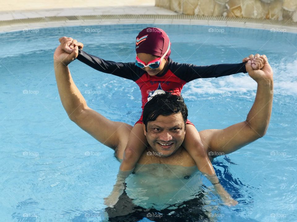 Father and daughter enjoying at swimming pool 