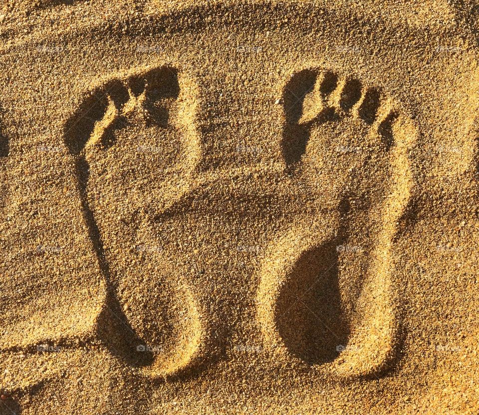 The sun casting shadows over my footprints in the sand. 