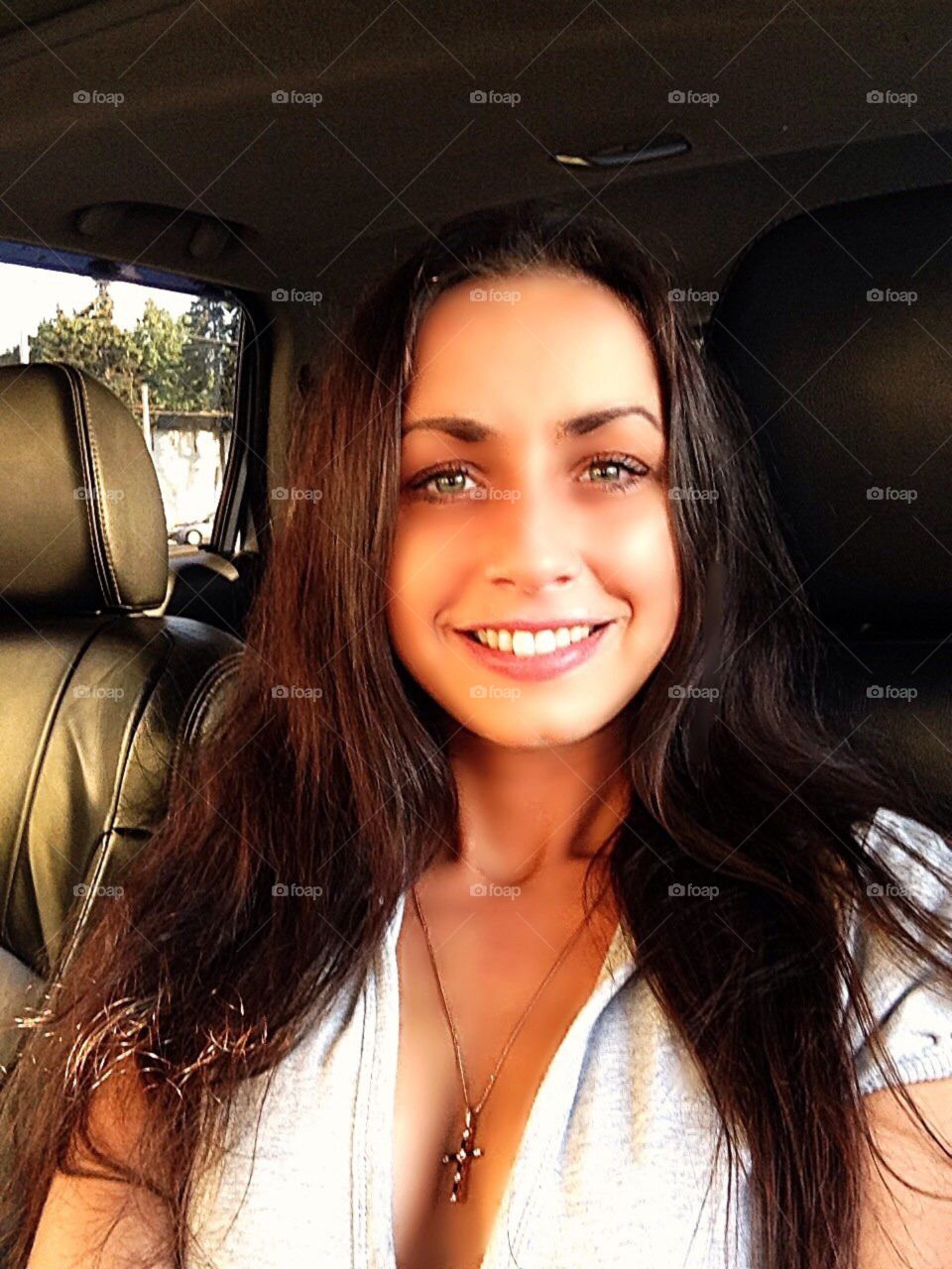 Young girl with long dark hair smiles in the car. Close-up