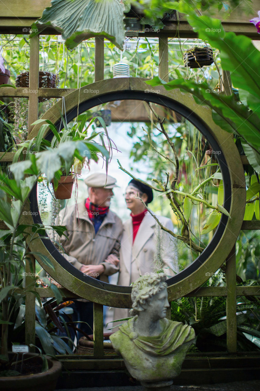 Captured and elderly couple in love through a circle in a garden.