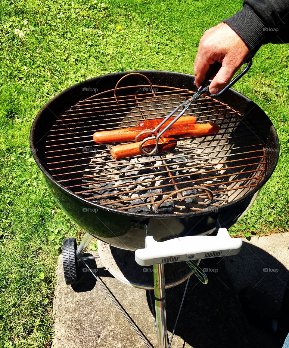 Grilling hot dogs on a charcoal grill in spring 