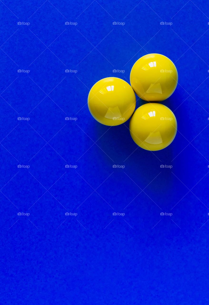 Three yellow balls on a blue table