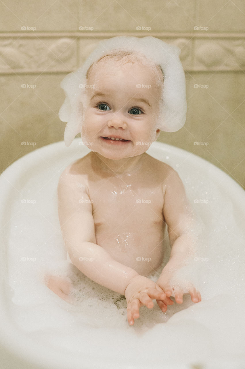 Cute smiling baby-girl with foam on head