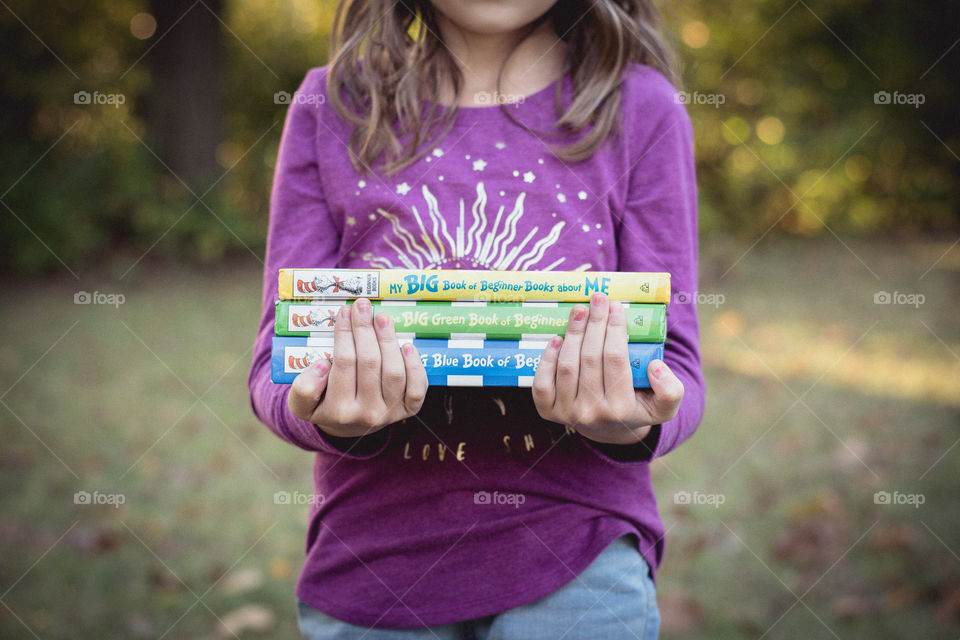 A girl holding a stack of Dr. Seuss books