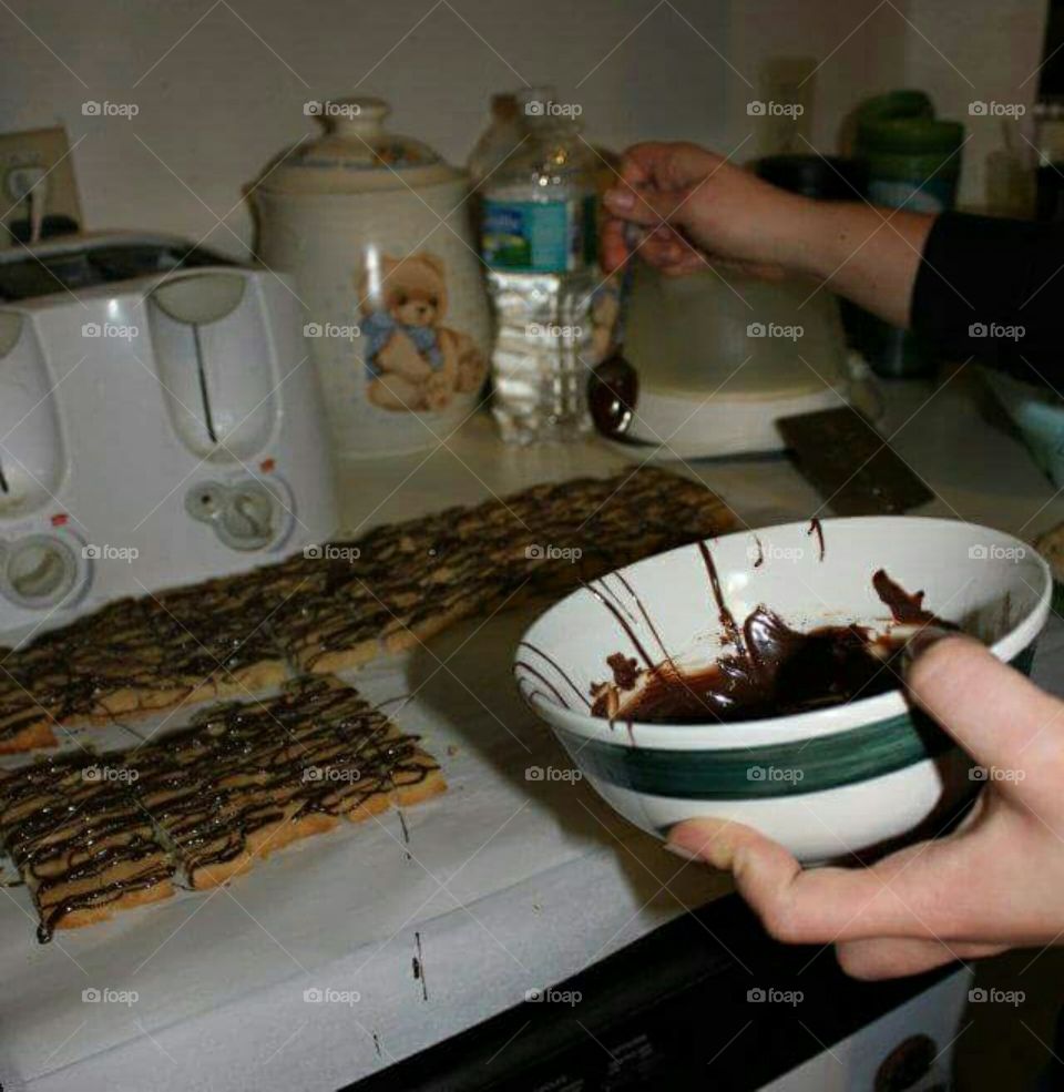 Adding chocolate to the top of the biscotti.