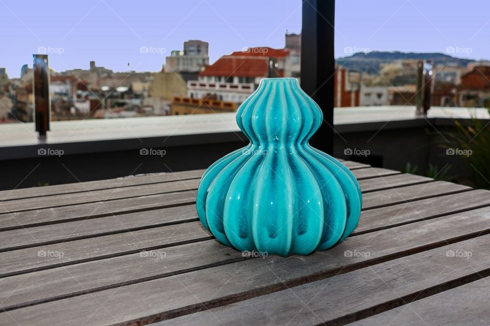 Beautiful turquoise vase on a wooden table in a terrace 