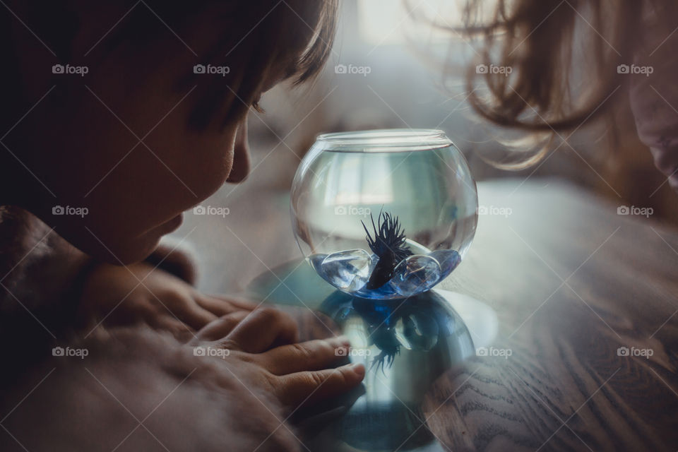 Girl with fish in round aquarium.