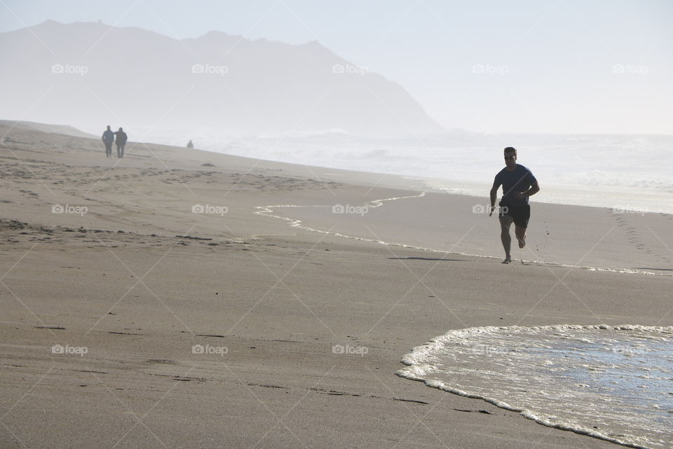 Running on a sandy beach while haze is covering slowly the shore