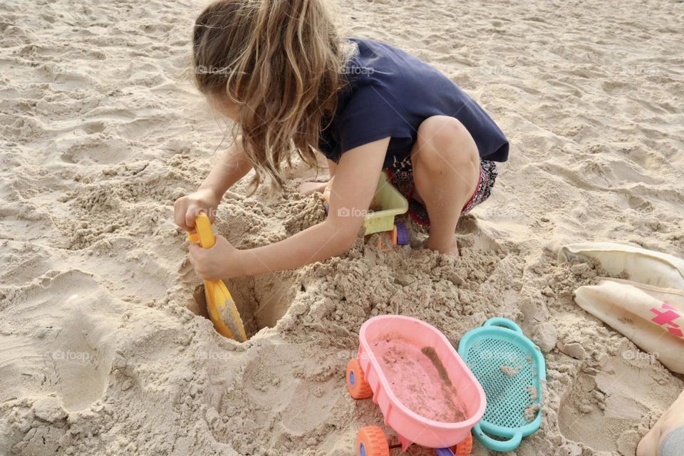 A girl digging hole at the beach 