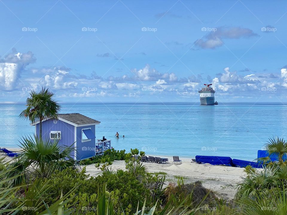 A beach in the Bahamas with a cruise ship in the background 