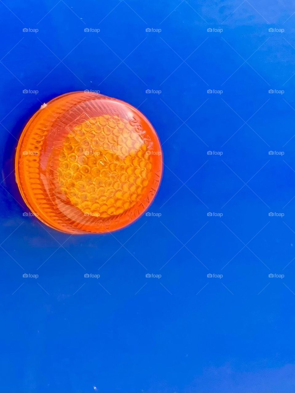 A circle orange reflection safety light on a blue car.