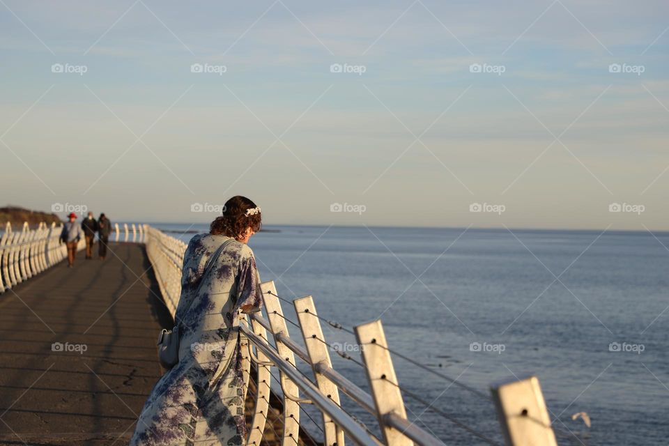 Young woman by the fence of breakwater 