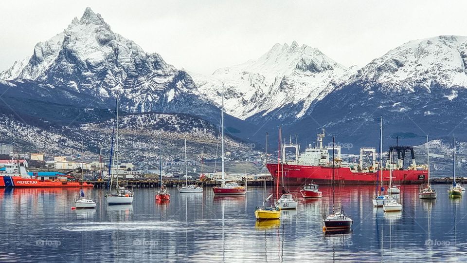 boats in the Beagle Channel, a fishing vessel in the dock of the city port, in the background the snow-capped mountains.