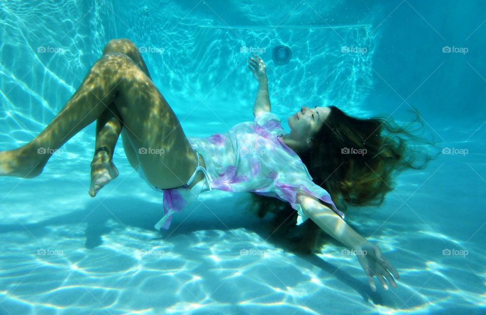 Young woman swimming underwater in the pool