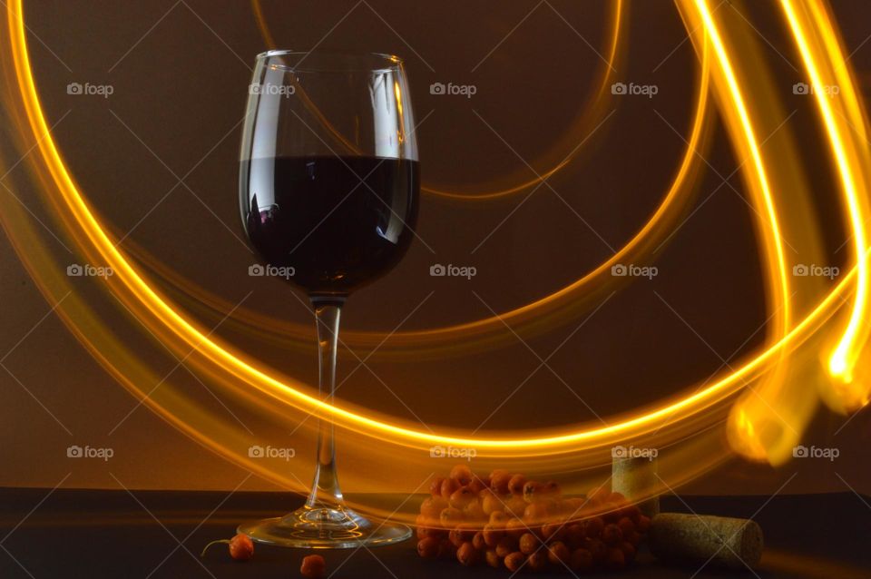 a glass of berry red wine in the dark with aromas floating in the air as light effects thanks to a slow shutter speed of 4 seconds.