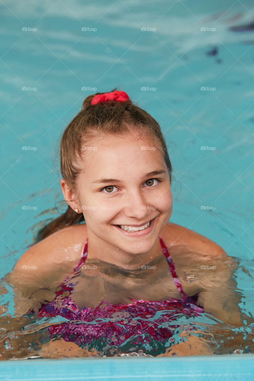 Young woman swimming and relaxing in swimming pool. Candid people, real moments, authentic situations