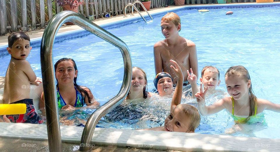 Group of children in swimming pool with victory sign