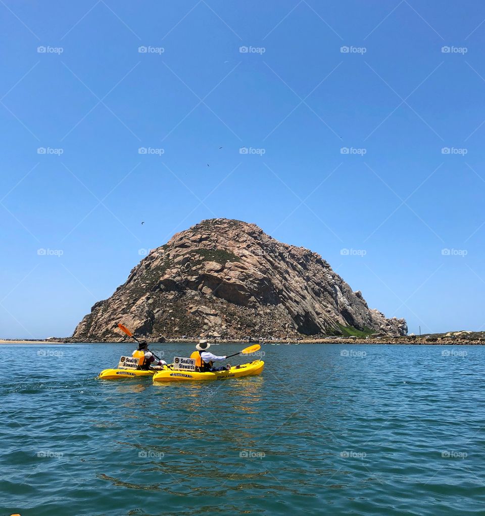 Kayaking in the ocean on two yellow kayaks heading towards the large landmark...the Rock in California 