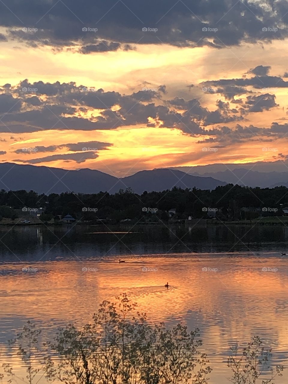 Orange sunset reflection on Lake with mts. In background.