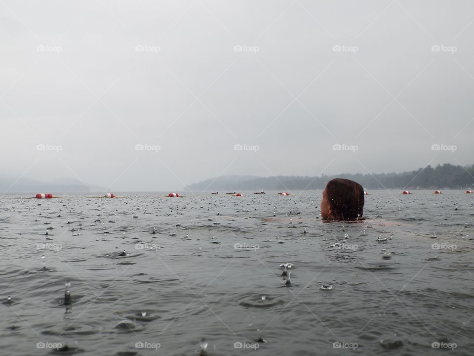 Woman swimming in lake in rain storm