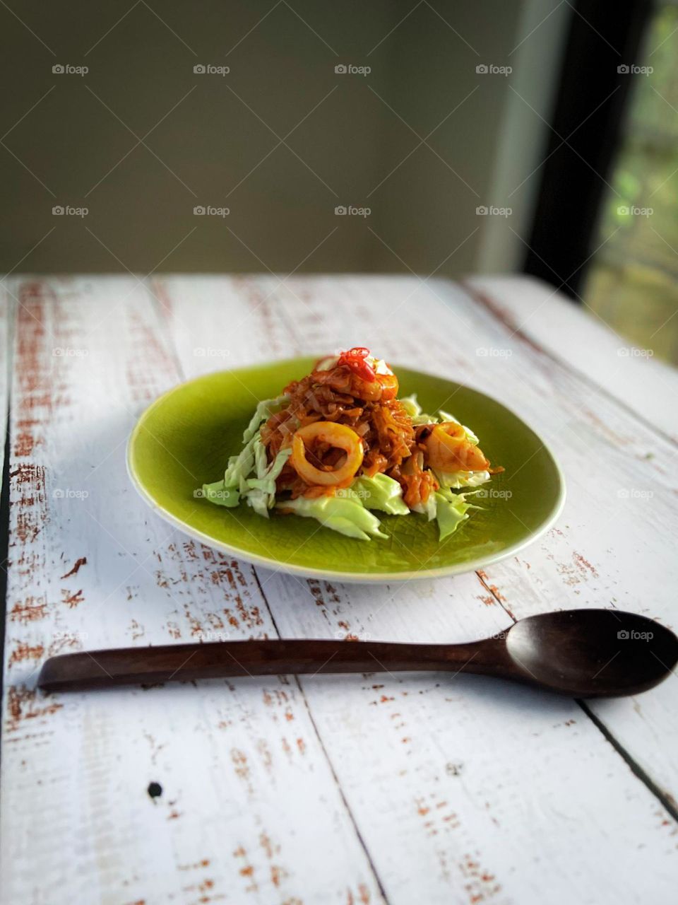 Seafood and flat noodle dish on a white wooden table. View from eye level