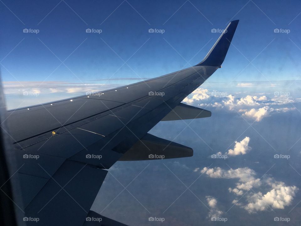 Wing view of a plane flying through a blue sky