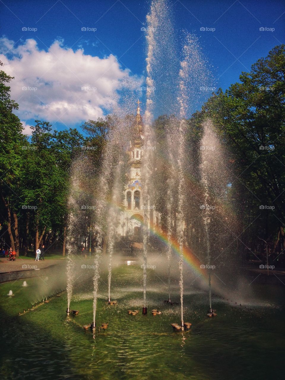 Scenic view of the beautiful double rainbow in a fountain in city against blue cloudy sky in autumn in Ukraine