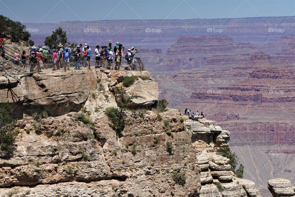 Tourists flock to a sightseeing area at the rim of Arizona's Grand Canyon on a perfect summer day