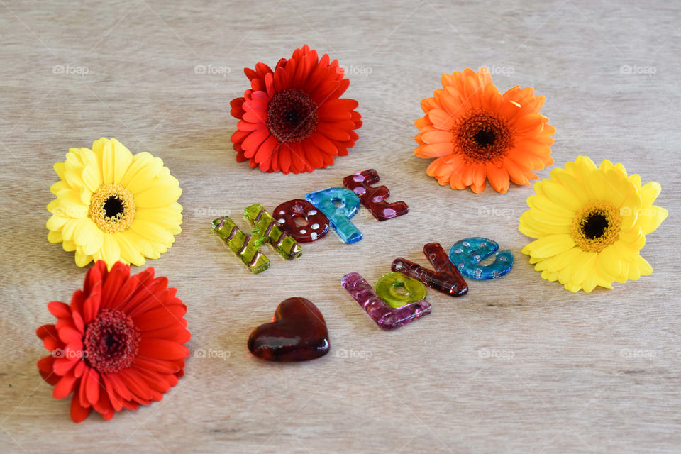 Flowers on wood background with art glass pieces spelling hope and love