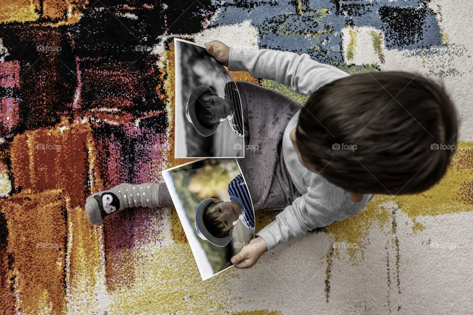 Boy holding two photographs