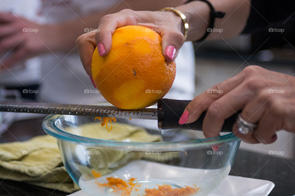 A woman is in the kitchen baking and cooking homemade scones with fruit and fresh herbs, scrapping orange peels