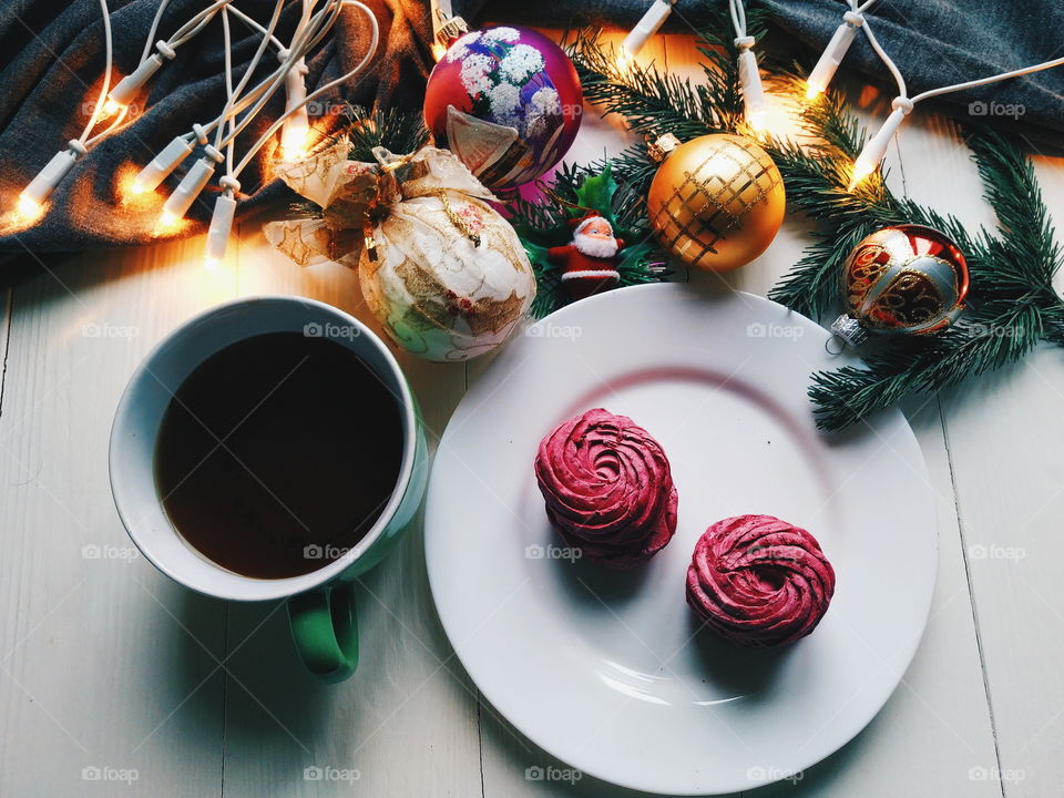 Christmas toys, a cup of hot tea, marshmallows and Christmas decorations on a white table