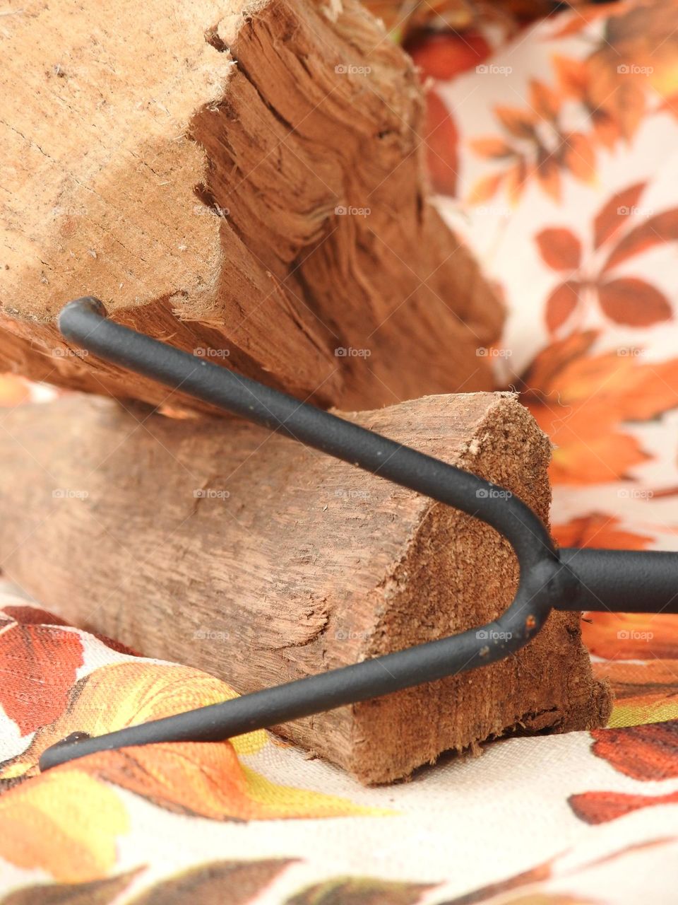 Autumn fall decor and cloth with logs and fire grate closeup with orange drawings of leaves.