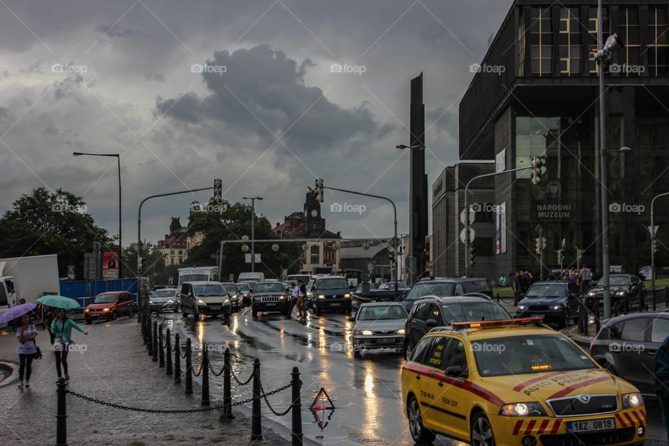Cars drive on the road which is wet from the rain.