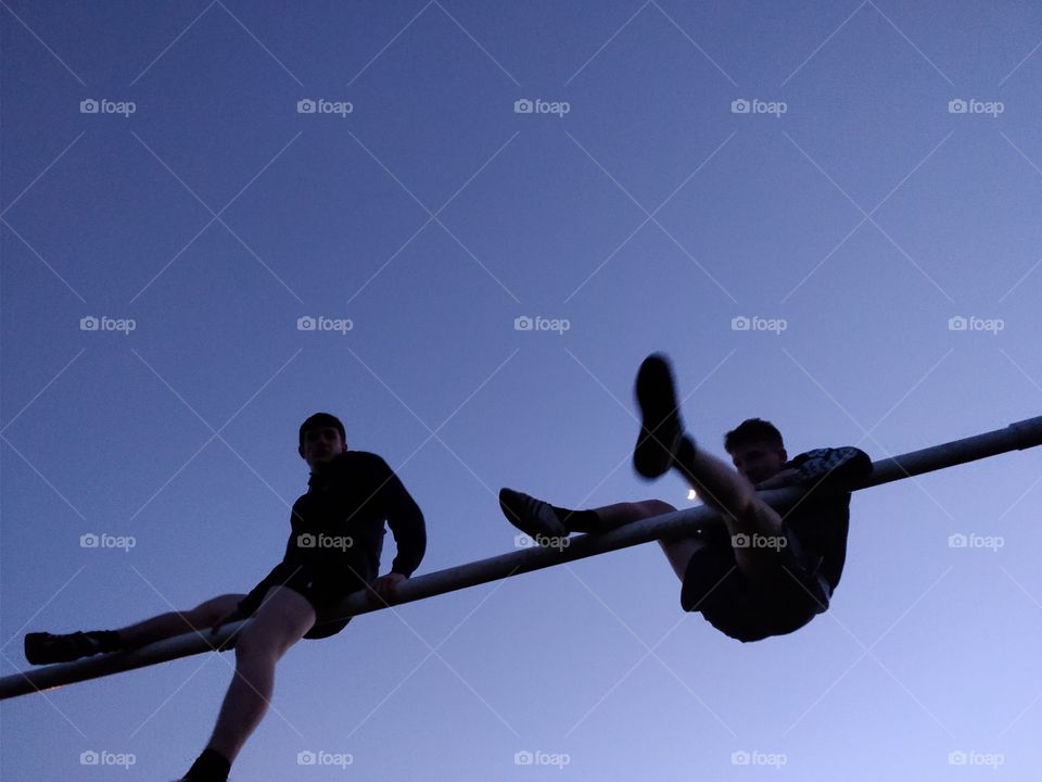 Climbing on a net, silhouetted figures, clear sky, action shot