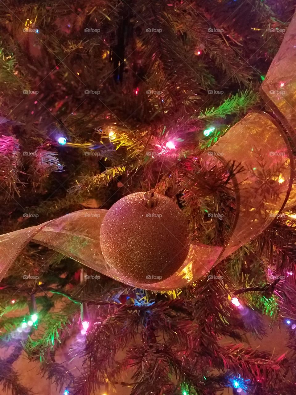 The glitter ornament and ribbon are so pretty with the lights glowing so brightly behind them. Love looking at Christmas trees when they are lit up so bright!