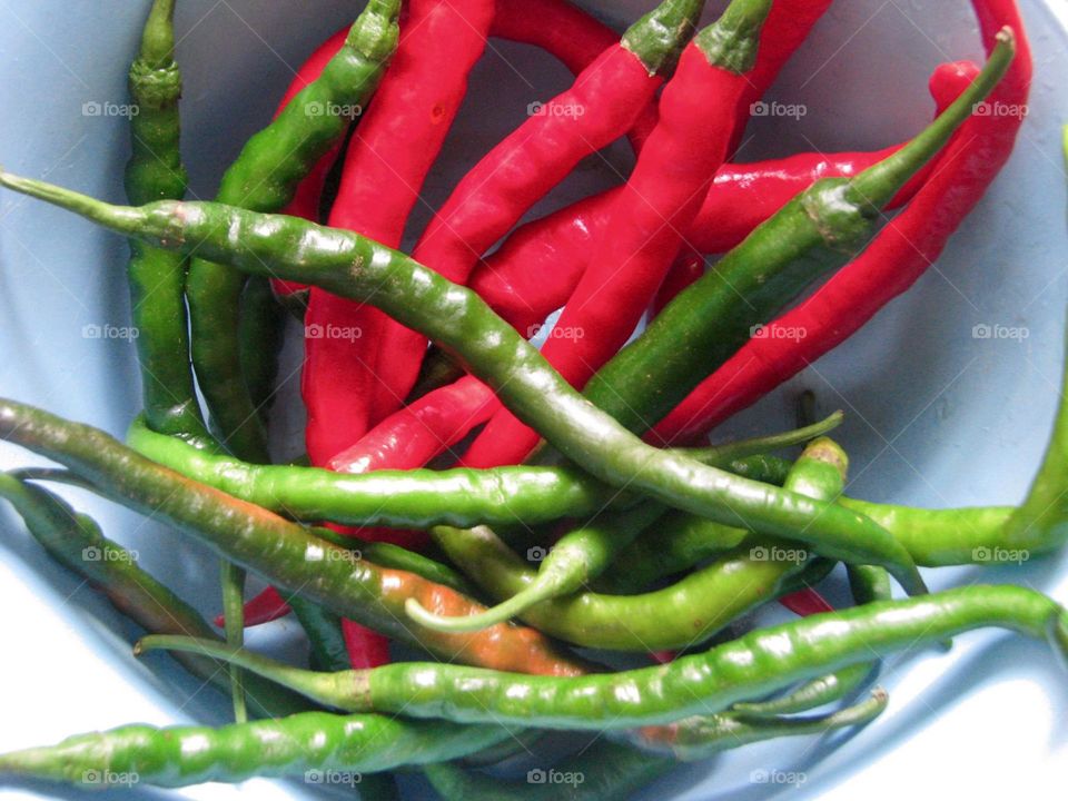 Close-up of a number of red and green chilies located in a white container in high angle view